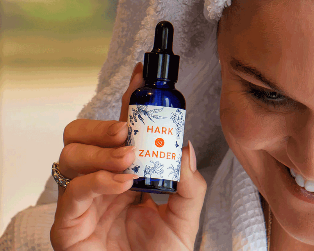 Woman holding a bottle labeled 'Hark & Zander' with a blurred background