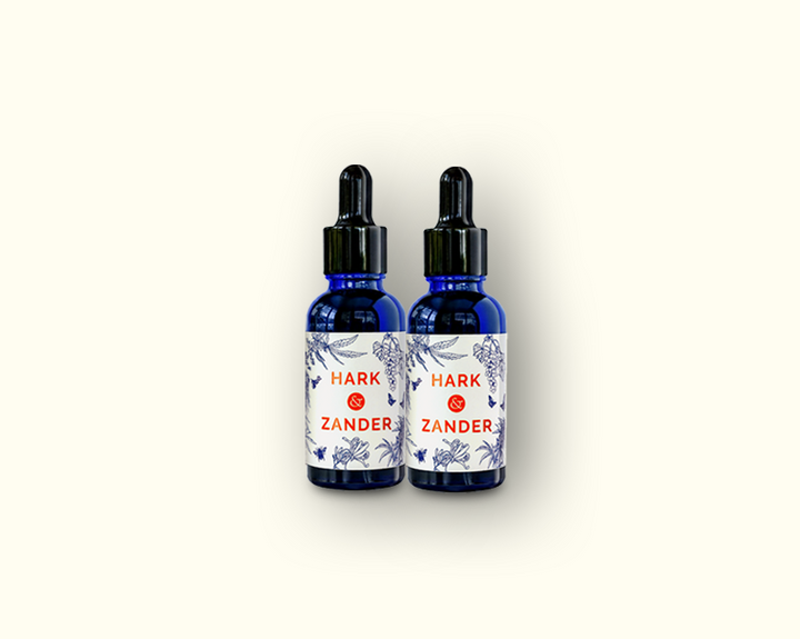 Two blue glass bottles with labels on a white background Hark & Zander